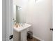 Elegant half bathroom featuring pedestal sink, decorative mirror, and modern fixtures at 25051 N 140Th Dr, Surprise, AZ 85387