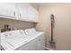 Bright laundry room featuring a white washer and dryer, white cabinets, and a cordless vacuum at 25225 S Glenburn Dr, Sun Lakes, AZ 85248