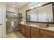 Main bathroom featuring dual copper sinks, granite countertops, a large mirror, and a tiled shower at 27023 N 130Th Gln, Peoria, AZ 85383