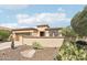 A tan single-story home features desert landscaping, a private courtyard, and an attached two-car garage at 27023 N 130Th Gln, Peoria, AZ 85383