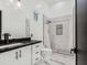 Modern bathroom with white cabinetry, black countertop, and glass-enclosed shower at 3518 N 201St Ln, Buckeye, AZ 85396