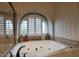 Bright bathroom featuring a large soaking tub under an arched window with plantation shutters at 5672 E Beverly Ln, Scottsdale, AZ 85254