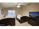 Well-lit bedroom with two beds, ceiling fan, TV, and a dresser, perfect for relaxation and entertainment at 5672 E Beverly Ln, Scottsdale, AZ 85254