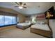 Bedroom with two beds, ceiling fan, window seat, and decorative wall art, creating a cozy atmosphere at 5672 E Beverly Ln, Scottsdale, AZ 85254