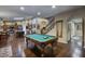 Open-concept game room featuring a pool table, hardwood floors, and seamless transition to the kitchen at 5672 E Beverly Ln, Scottsdale, AZ 85254