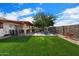 Backyard features an artificial grass area with outdoor seating, BBQ, and mature tree for shade at 5808 W Acoma Dr, Glendale, AZ 85306