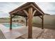 A beautiful wooden gazebo sits next to a sparkling pool with a stone waterfall feature at 9041 W Redbird Rd, Peoria, AZ 85383