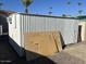 A white metal storage building sits on gravel with an AC unit and some discarded materials in front of it at 9501 E Broadway Rd # 21, Mesa, AZ 85208