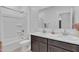 Modern bathroom with double sinks, dark cabinets, marble countertop, and a tub with a white shower surround at 10004 S Smythe Dr, Apache Junction, AZ 85120