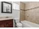 Well-lit bathroom featuring tiled walls, a vanity with a dark wood cabinet, and a shower-tub combo at 1002 W Villa Rita Dr, Phoenix, AZ 85023