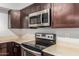 Kitchen featuring a modern range and stainless steel microwave and dark cabinetry at 1002 W Villa Rita Dr, Phoenix, AZ 85023