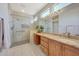 Well-lit bathroom features a glass shower, granite counters, wood cabinets, and views into the walk-in closet at 16313 W Escondido Ct, Surprise, AZ 85374