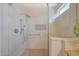 A frameless glass shower showcases designer tile, a rainfall showerhead, and grab bars for accessibility at 16313 W Escondido Ct, Surprise, AZ 85374