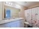 Well lit bathroom with double sink vanity, a large mirror and shower with floral curtain at 1652 E Judi St, Casa Grande, AZ 85122