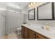 Bathroom featuring a shower, a double-sink vanity with wooden drawers, and a large mirror at 18390 W Hayden Dr, Surprise, AZ 85374