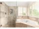 Bright bathroom boasts a glass-enclosed shower, soaking tub, and shuttered windows at 2026 E Cortez Dr, Gilbert, AZ 85234