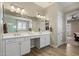 Bathroom featuring a dual vanity with white cabinets, white countertops, and views into the ensuite bedroom at 22925 N 46Th St, Phoenix, AZ 85050