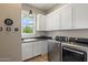 Laundry room with white cabinets, black countertops, and stainless steel washer and dryer units at 22925 N 46Th St, Phoenix, AZ 85050