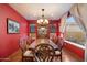 Elegant dining room with red walls, a large wooden table, and a chandelier, perfect for Gathering gatherings at 35206 N 27Th Ave, Phoenix, AZ 85086