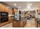 Open kitchen featuring an island with granite countertops, wood cabinets, and stainless steel appliances at 35206 N 27Th Ave, Phoenix, AZ 85086