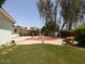 Well-maintained backyard with grass, lush trees, and circular patio area for outdoor entertaining at 3741 W Davidson Ln, Phoenix, AZ 85051