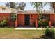 Close-up of a red brick home highlighting the front door, decorative columns, and vibrant flower beds at 3741 W Davidson Ln, Phoenix, AZ 85051