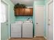Functional laundry room with washer, dryer, overhead cabinets, and access to multiple doors at 3741 W Davidson Ln, Phoenix, AZ 85051