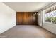 Spacious living room with vintage wooden wall accents, a large window, and neutral carpet flooring at 3741 W Davidson Ln, Phoenix, AZ 85051