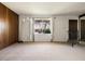 Spacious living room with carpet, paneled wall, unique floor lamp, and ironwork on window at 3741 W Davidson Ln, Phoenix, AZ 85051