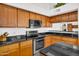 Well-equipped kitchen with stainless steel appliances, black granite countertops, and wood cabinets at 3926 E Lavender Ln, Phoenix, AZ 85044