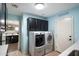 Charming laundry room with blue walls, black cabinets, stacked washer and dryer, and 