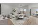 Bright living room features wood floors, white sectional sofa, and neutral decor at 42405 W Peters Dr, Maricopa, AZ 85138