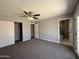 A spacious bedroom with neutral walls, carpet, closet, ceiling fan and a view into the bathroom at 5815 N 21St Ave, Phoenix, AZ 85015