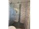 A walk-in shower with gray tile walls, black mosaic floor, and glass door at 5815 N 21St Ave, Phoenix, AZ 85015