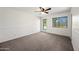 Spacious carpeted bedroom with a ceiling fan, door and window offering natural light at 6160 E Inglewood St, Mesa, AZ 85205