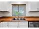 Close-up of a stainless steel kitchen sink with wood countertops and white cabinets at 6160 E Inglewood St, Mesa, AZ 85205
