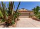 Beige home featuring a two-car garage and well-maintained desert landscaping, complete with various cacti and shrubbery at 630 E Jensen St # 102, Mesa, AZ 85203