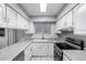 Galley kitchen featuring white cabinetry, stainless steel appliances and speckled countertops at 810 W Villa Maria Dr, Phoenix, AZ 85023