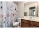 Bathroom with a floral shower curtain, wood cabinets, and tile flooring at 829 S 111Th Dr, Avondale, AZ 85323