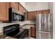 Kitchen featuring stainless steel refrigerator, black range, and wooden cabinets at 829 S 111Th Dr, Avondale, AZ 85323
