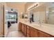 Bathroom with double sinks, a large mirror, and a doorway to the Primary bedroom, offering convenience and style at 17009 W Eureka Springs Dr, Surprise, AZ 85387