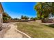 Lush green backyard with gravel, mature trees, and well-manicured lawn, ideal for relaxation and outdoor gatherings at 19903 S 187Th Dr, Queen Creek, AZ 85142