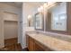 Bathroom featuring granite counters, dual mirrors, a walk-in closet, and wood flooring at 23929 W Twilight Trl, Buckeye, AZ 85326