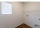 Clean laundry room with a window, wooden floors, and bright white walls at 23929 W Twilight Trl, Buckeye, AZ 85326