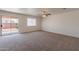 Bright living room featuring neutral carpet, a ceiling fan, and a sliding glass door at 23929 W Twilight Trl, Buckeye, AZ 85326