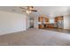 Expansive living area with neutral carpeting connecting to a kitchen with stainless appliances and wood cabinets at 23929 W Twilight Trl, Buckeye, AZ 85326