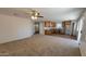 Spacious living room with carpet flooring, ceiling fan, and a view of the modern kitchen at 23929 W Twilight Trl, Buckeye, AZ 85326