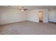 Large living room with neutral carpet, a ceiling fan, and a doorway to an adjacent room at 23929 W Twilight Trl, Buckeye, AZ 85326