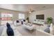 Staged living room with modern furniture, neutral tones, and a sliding glass door at 23929 W Twilight Trl, Buckeye, AZ 85326