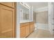 Bright bathroom with double sinks, light wood cabinetry, and a shower over tub at 2511 W Queen Creek Rd # 378, Chandler, AZ 85248